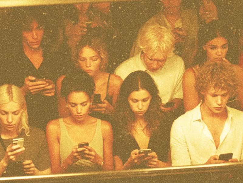 Group of people staring at phones with blue screen light illuminating their faces and skin
